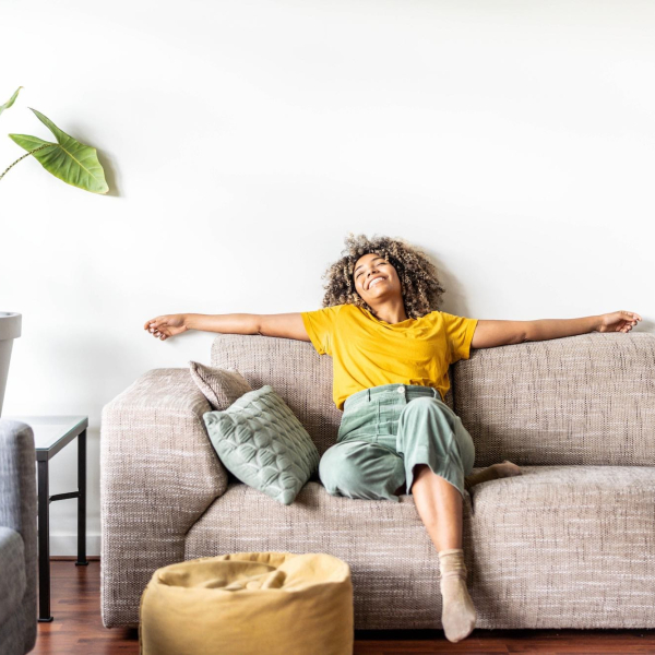 Happy Afro American Woman Relaxing On The Sofa At Home - Smiling Girl Enjoying Day Off Lying On The Couch - Healthy Life Style, Good Vibes People And New Home Concept